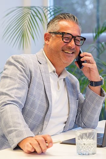 Professionele man in een grijs colbert voert een telefoongesprek, mogelijk over het Digitaal Product Paspoort.